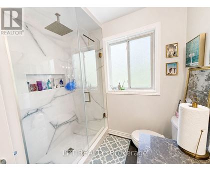 A bathroom with a marble shower and a toilet with a towel holder.
