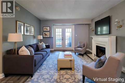 A living room with a blue carpet and a fireplace.