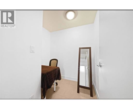 A bedroom with a bed, chair and mirror.