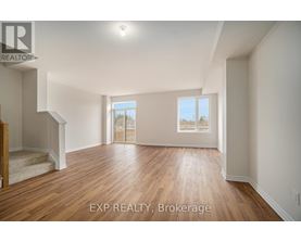 A spacious room with wooden flooring and a staircase leading to another level.