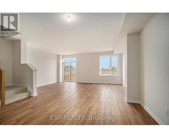 A spacious room with wooden flooring and a staircase leading to another level.