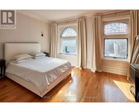 A bedroom with a large bed and a window with a view of trees.