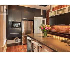A modern kitchen with a stainless steel refrigerator and a wooden floor.