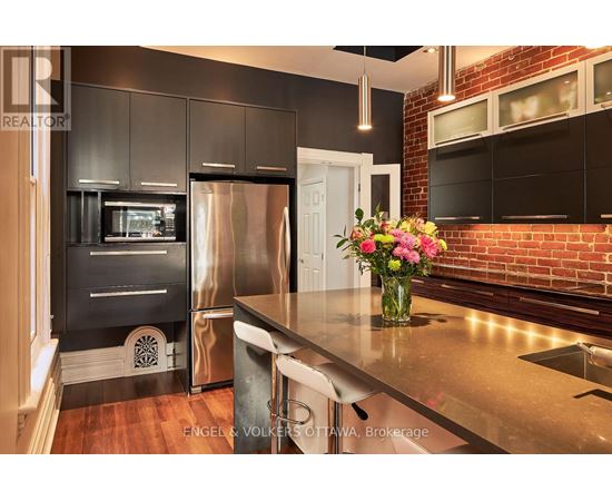 A modern kitchen with a stainless steel refrigerator and a wooden floor.