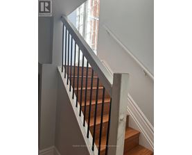 A staircase with a wooden handrail and white walls.