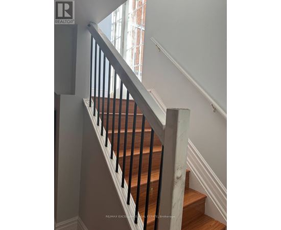 A staircase with a wooden handrail and white walls.