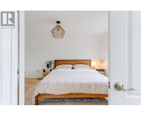 A bedroom with a bed, nightstand, and a hanging light fixture.