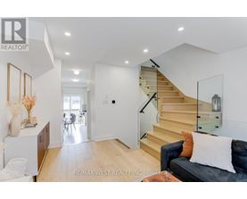 A living room with a couch, a staircase, and a dining area.