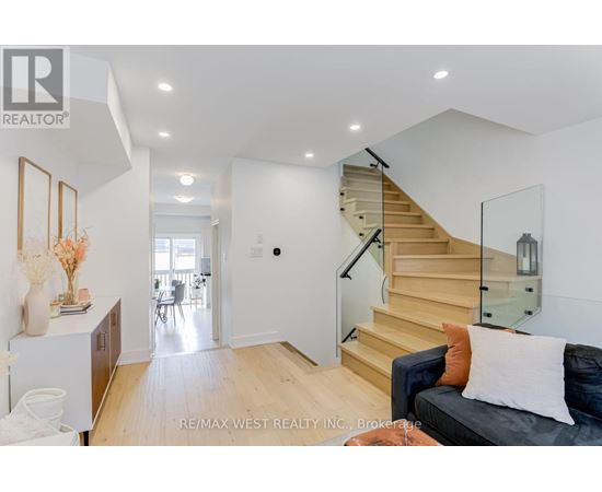 A living room with a couch, a staircase, and a dining area.