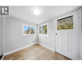 A room with a white door and a window with a view of trees.