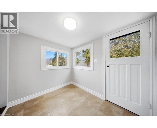 A room with a white door and a window with a view of trees.
