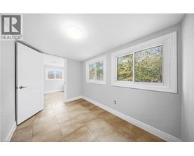 A room with a white door, a window with a view of trees, and a tiled floor.