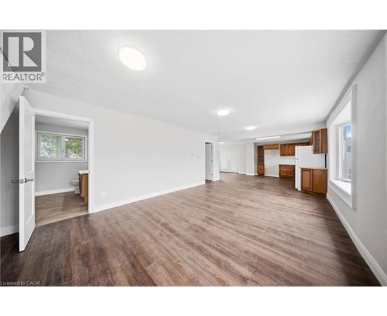 A spacious room with wooden flooring and white walls.
