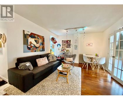 A living room with a brown couch and a painting on the wall.