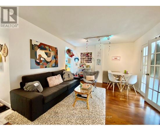 A living room with a brown couch and a painting on the wall.