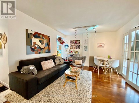 A living room with a brown couch and a painting on the wall.