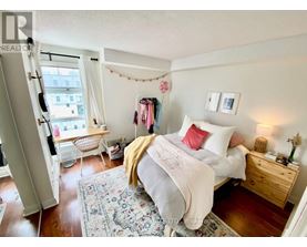 A bedroom with a bed, nightstand, and chair.