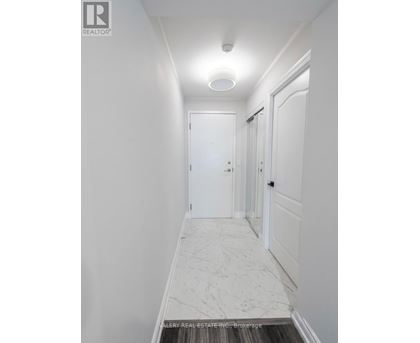 A hallway with marble flooring and white walls.