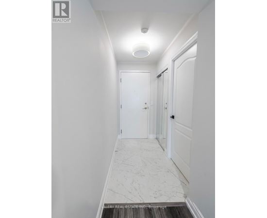 A hallway with marble flooring and white walls.
