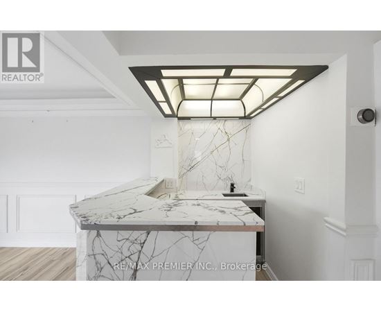 A white marble countertop with a modern kitchen island and a skylight above it.