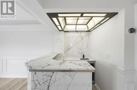A white marble countertop with a modern kitchen island and a skylight above it.