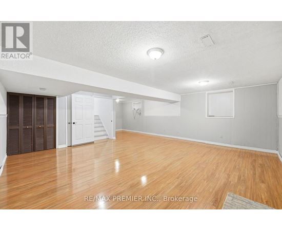 A spacious room with wooden flooring and white walls.