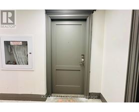 A grey door with a keypad on the right side and a small window on the left side.