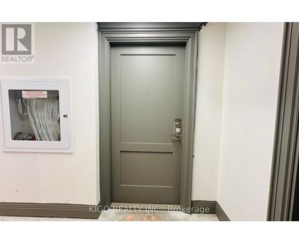 A grey door with a keypad on the right side and a small window on the left side.
