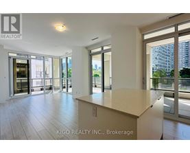 A spacious room with a large island in the middle and sliding glass doors leading to a balcony.