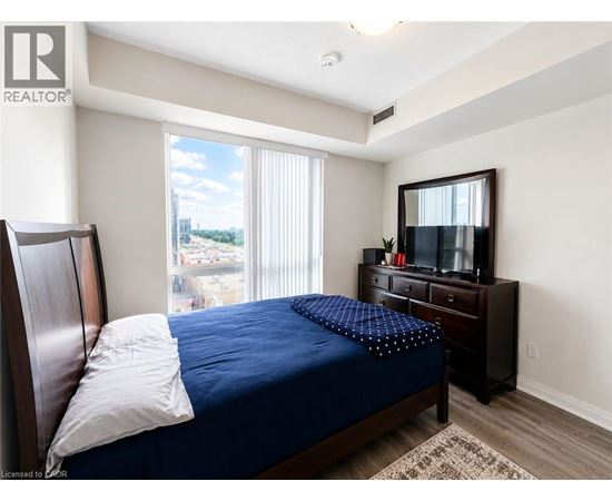 A bedroom with a bed, dresser, and window with blinds.