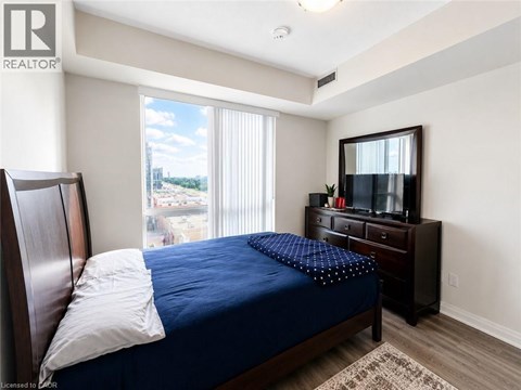 A bedroom with a bed, dresser, and window with blinds.