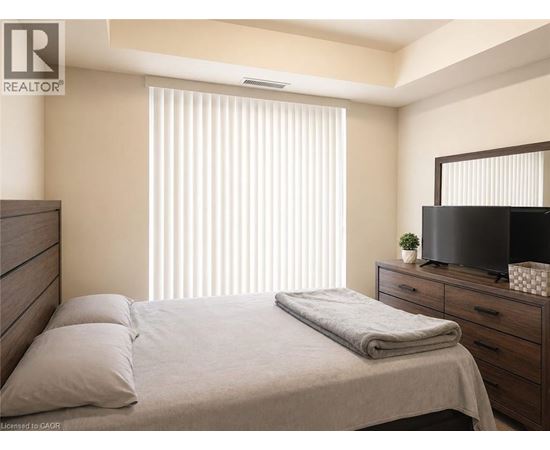 A bedroom with a bed, a dresser, and a television.