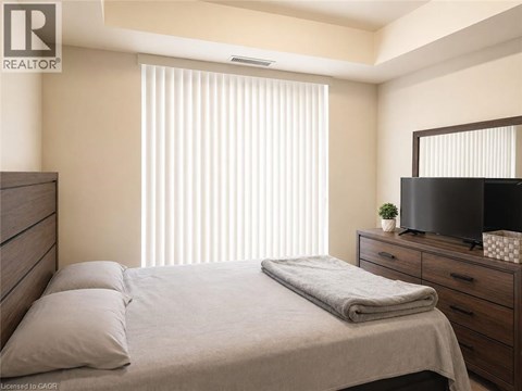 A bedroom with a bed, a dresser, and a television.
