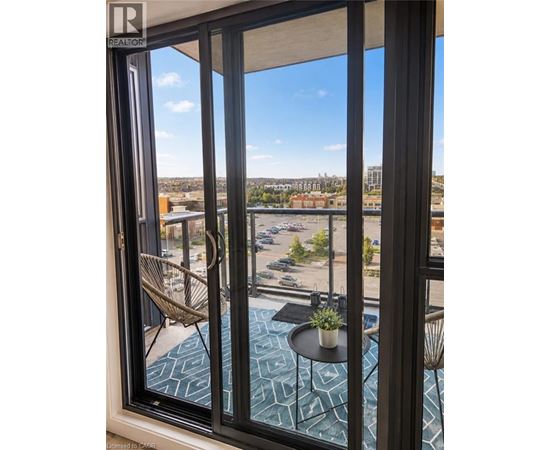 A balcony with a table and chairs overlooking a parking lot.