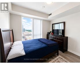 A bedroom with a bed, dresser, and window overlooking a parking lot.