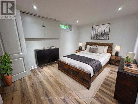 A bedroom with a bed, nightstand, and a plant.