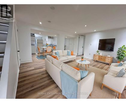 A living room with a white couch and a television on the wall.