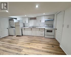 A kitchen with white cabinets and appliances, and a wooden floor.