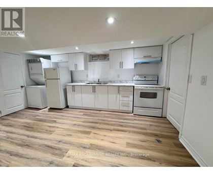 A kitchen with white cabinets and appliances, and a wooden floor.