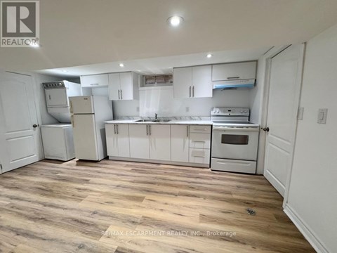 A kitchen with white cabinets and appliances, and a wooden floor.