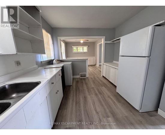 A kitchen with white cabinets and a wooden floor.