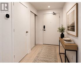 A hallway with a rug, a table with a plant, and a painting on the wall.