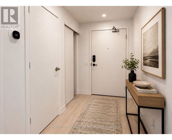 A hallway with a rug, a table with a plant, and a painting on the wall.