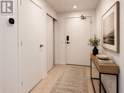 A hallway with a rug, a table with a plant, and a painting on the wall.