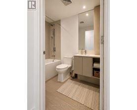 A white toilet is in a bathroom with a white tub and a white sink.