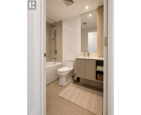 A white toilet is in a bathroom with a white tub and a white sink.