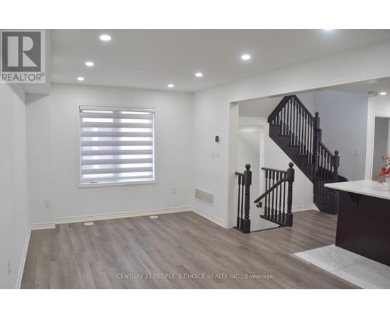 A spacious room with a staircase and a window with blinds.