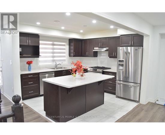 A modern kitchen with dark brown cabinets and stainless steel appliances.
