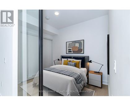 A bedroom with a bed, nightstand, and lamp.