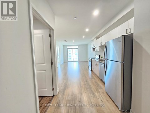 A kitchen with a refrigerator on the right side and a door on the left.